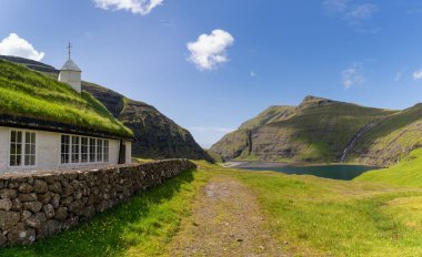 Saksun 'daki tarihi Luteryan kilisesi ve Faroese Adasındaki Pollurin Gölü manzarası.