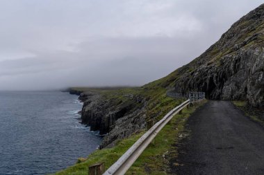 Faroe adası takımadalarındaki Sandoy Adası 'ndaki Skardanes köyüne giden engebeli ve dar bir yol.