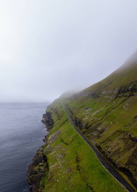 Faroe Adaları 'ndaki Husavikervegur Karayolu ve Sandoy Adası' nın engebeli kıyı şeridinin dikey görüntüsü.