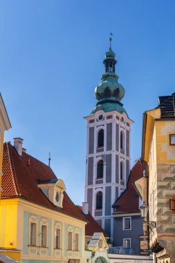 Cesky Krumlov, Çek Cumhuriyeti - 3 Ekim 2025: Cesky Krumlov 'un tarihi şehir merkezindeki St. Vitus Kilisesi çan kulesi ve renkli binaların dikey görünümü