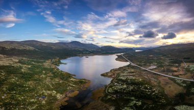 Günbatımı insansız hava aracı Norveç 'in vahşi doğasında tundralar, göller ve içinden geçen yalnız bir otoyol.