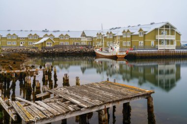 Siglufjordur, İzlanda - 16 Temmuz 2025: Siglufjordur 'daki liman ve otelin ön planda bir balıkçı teknesiyle manzarası