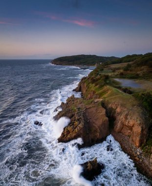Günbatımında Danimarka 'nın engebeli kıyı şeridi ve kuzey kıyısındaki Bornholm adasının kayalıklarından gün batımı manzarası