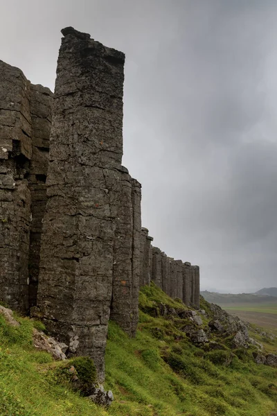 Batı İzlanda 'daki Snaefellsnes Yarımadası' ndaki Gerduberg uçurumlarındaki engebeli dolerit bazalt kaya sütunlarının dikey görüntüsü.