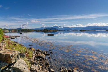 Onarheim yakınlarındaki Vestland County 'de manzaralı Hardangerfjord ve ses manzarası ön planda küçük bir ada ve kayıkla