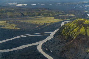 İzlanda 'nın yüksek kesimlerindeki volkanik dağların volkanik kum ve kül yataklarında akan dere ve nehirlerle kaplı yeşil yosun kaplı görüntüsü.