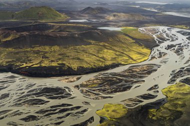 İzlanda 'nın yüksek kesimlerindeki volkanik dağların volkanik kum ve kül yataklarında akan dere ve nehirlerle kaplı yeşil yosun kaplı görüntüsü.