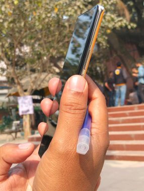 Bulanık Arkaplan ile Açık havada Akıllı Telefonu Tutan Kişi