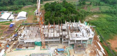 İnşaat halinde bir bina ve vinç olan bir inşaat alanının havadan görüntüsü.