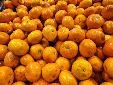 Büyük bir taze portakal yığını, canlı ve olgun, çerçeveyi dolduruyor..