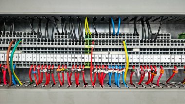Endüstriyel elektrik kontrol paneli içindeki karmaşık kablo ve terminal blokları organize kablo yönetimi ve elektrik bağlantılarını gösteriyor.