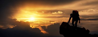 Yürüyüşçülerin silueti gün batımında dağ yamacına tırmanıyor. Yaşam limitleri ve yürüyüş başarısı kavramı tam, kopyalama alanı olan spor afişi