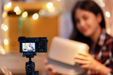 Vlogger Asyalı Kadın mutluluğu üç ayaklı kamerayla internetten para kazanırken. Canlı Yayın ve vloglama kavramı.
