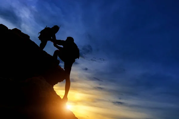 Sylwetka Drużyny Wspinaczkowej Pomagającej Sobie Nawzajem Podczas Wspinaczki Zachodzie Słońca — Zdjęcie stockowe
