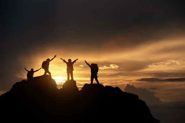 ハイカーのシルエットの山の崖を登る 日没の中に登る登山グループを助け合う 助けとチームワーク 人生とハイキングの成功の限界の概念 — ストック写真
