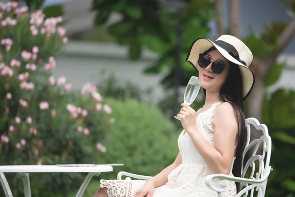 Asyalı genç bir kadın bahçede oturmuş su bardaklarıyla rahatlıyor. Yaşam Tarzı İnsanlar, İnsanların Sağlığı.