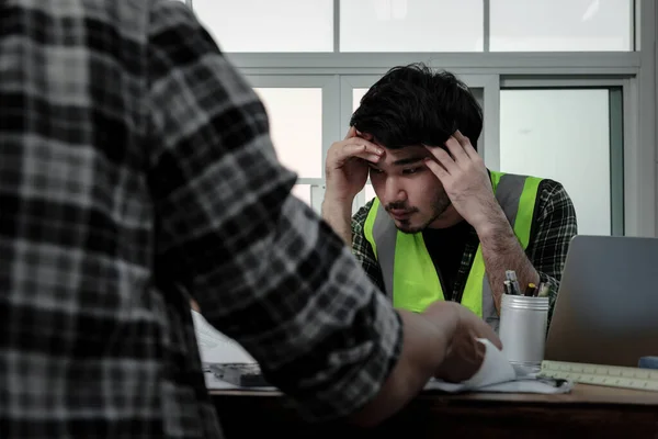 Stressful of engineer people in panic while meeting at the office, Young employee holding hands on his head with stress while sitting at the desk.