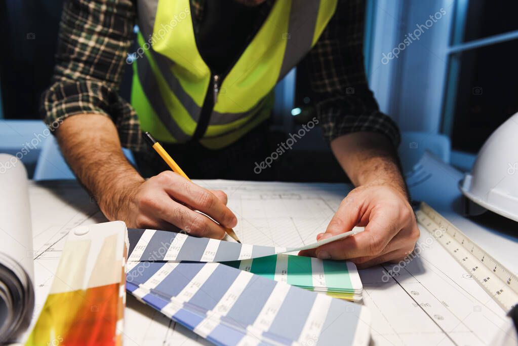 Engineer Designer sketching with Blueprint Architecture on Desk office in-home at night, Working overtime, Maximum working hours, Compulsory overtime.