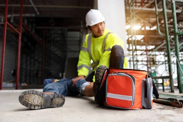 First aid support accident at work of construction worker at site. Builder accident falls scaffolding on floor, Safety team helps employee accident.