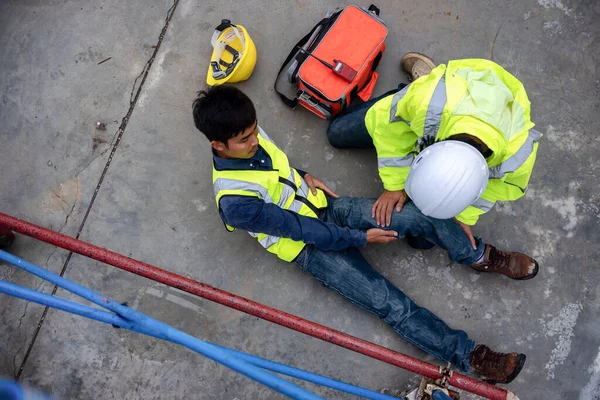 First aid support accident at work of construction worker at site. Builder accident falls scaffolding on floor, Safety team helps employee accident.