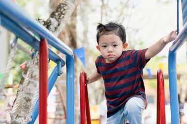 Asyalı çocuk portresi. Yorgun surat ifadesi. Park 'ta çocuklar için oyun parkında oynayan küçük çocuk.