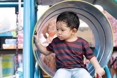 Asyalı çocuk portresi. Yorgun surat ifadesi. Park 'ta çocuklar için oyun parkında oynayan küçük çocuk.