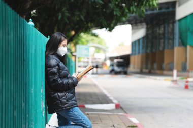Koronavirüs salgını sırasında açık havada bulaşıcı hastalıklara karşı maske takan liseli öğrenciler okulda tek başlarına okuyorlar. Öğrencilerin yeni normal hayatı.