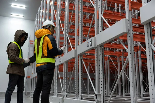 Maintenance technician service in cold warehouse storage, Machinery engineering people checking moving rack system and equipment in warehouse.