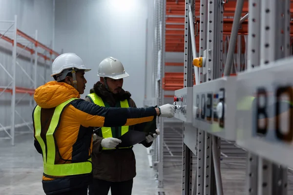 Maintenance technician service in cold warehouse storage, Machinery engineering people checking moving rack system and equipment in warehouse.