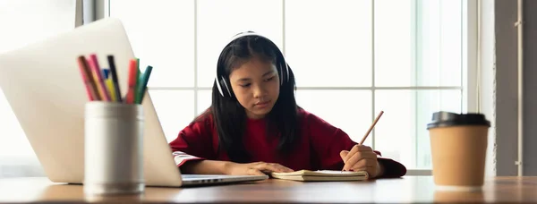 女生们戴着耳机 坐在桌旁学习和记笔记 在围观大流行期间用笔记本电脑做作业 并把学生们在网上的新生活 社交距离和新生活锁起来 横幅尺寸 — 图库照片