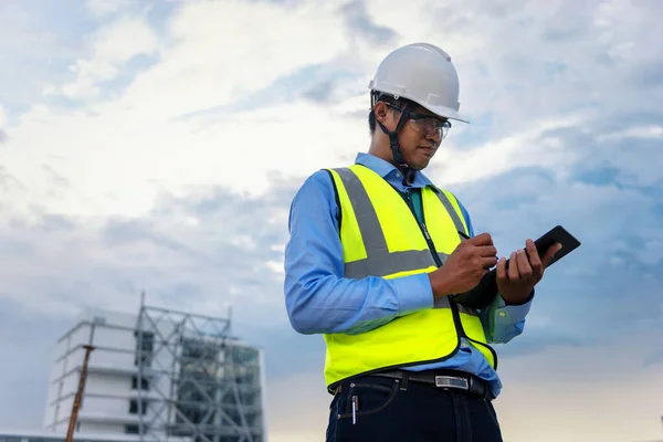 Engineering Consulting People on construction site holding tablet in his hand. Building inspector. Construction site checking by technology and business workflow of new building.