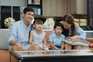 Mutlu bir aile evlerin oturma odasındaki kanepede oturup televizyon şovu ve eğlenceyi birlikte seyrediyor. Ebeveynler çocuklarına bakar ve aile içinde faaliyetler oluştururlar..