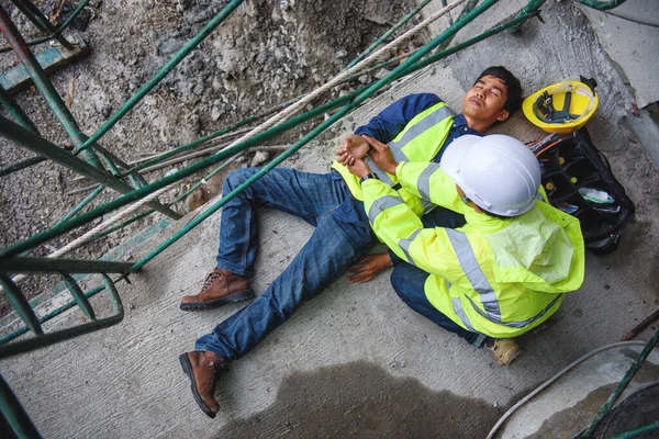 Check Response and pulse, Life-saving, and rescue methods. Builder accident falls scaffolding on floor, Safety team helps employee accident. First aid support accident in Construction work.
