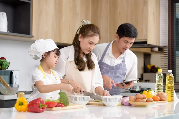 亚洲父母正在教女儿如何轻松地在家做饭 同时研究如何在平板电脑上做饭 一家人喜欢在家里的厨房里一起做饭 专注于母亲中心 — 图库照片