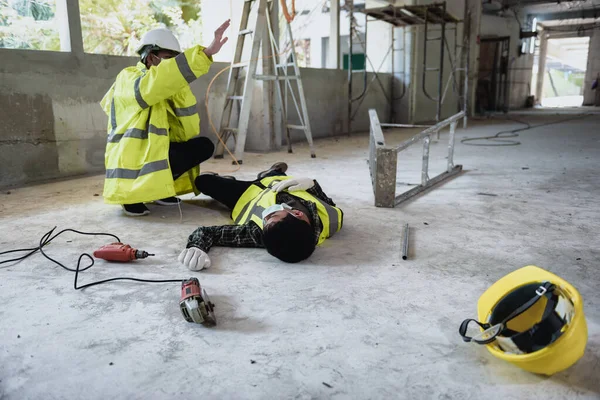 Work accidents of worker in workplace at construction site area and Unconscious with colleague motion and call to the safety officer for rescue and Life-saving. Selection focus on an Injured person.