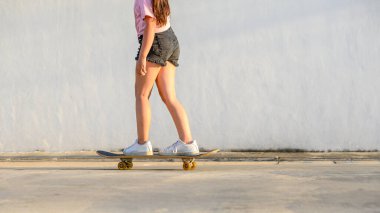 Gün batımında ya da akşam evin yakınında denge kurarken kaykay oynayan yakın plan kız çocuğu..