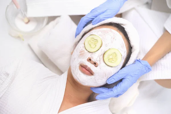 年轻的亚洲妇女得到面部护理 面部面具 和温泉美容治疗软滑柔滑柔滑的皮肤 自创面罩应用于疲劳眼的黄瓜片眼罩 — 图库照片