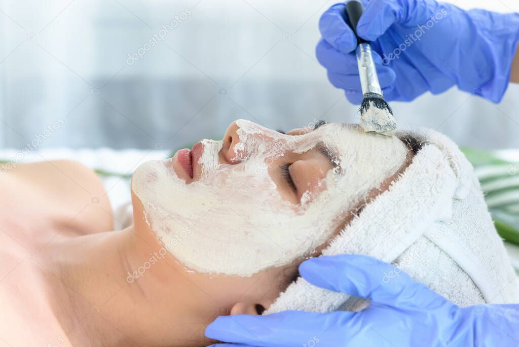 Young Asian Women getting facial care, Facial masks, and spa beauty treatment for soft smooth silky skin by beauticians at spa salon. Beauty skincare concept