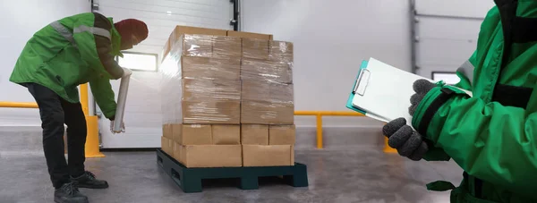 Personel, film paketleme kutularını pankarttaki soğuk hava deposunda notla paketliyor, malları yüklüyor, dondurucu odada depolama hazırlıyor, Lojistik İş Konseptinde Depo Depolama Sistemi Servisi