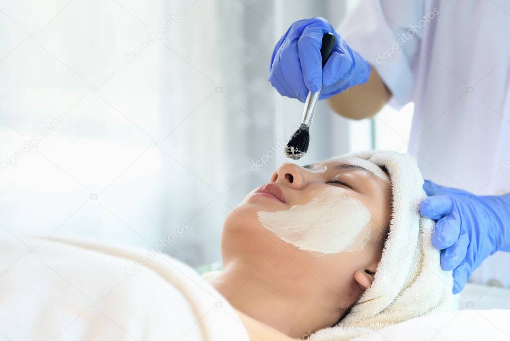 Young Asian Women getting facial care, Facial masks, and spa beauty treatment for soft smooth silky skin by beauticians at spa salon. Beauty skincare concept