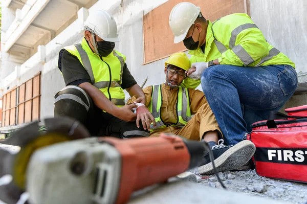 手の出血 作業中の事故の後に労働者を構築するための応急処置チームのサポート 建設現場での建設電力ツール安全で過失を使用しています 作業コンセプトの安全性 — ストック写真