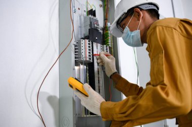 Elektrik mühendisi kontrol panelinde elektrik tesisatı ve elektrik tesisatı denetimi için dijital çoklu metre test akımı kullanıyor..
