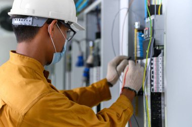 Elektrik mühendisi elektrik tesisatlarını ve elektrik tesisatını test etmek için kontrol panelinde dijital çoklu metre test akımı kullanıyor..