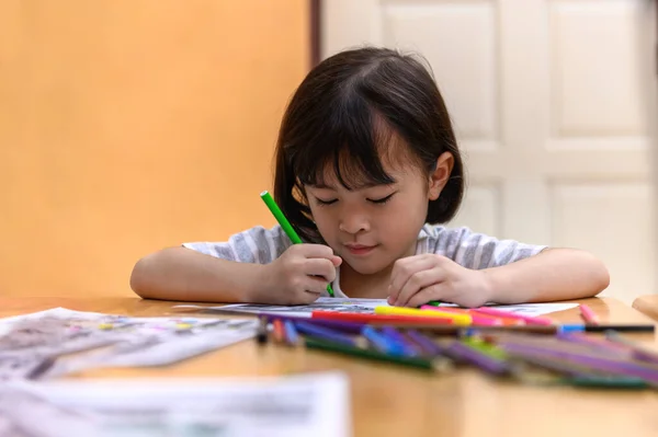 亚洲小女孩坐着练习他们的技巧 把注意力集中在桌上的彩纸上 学前儿童在家学习写作和阅读 艺术教育和创造力 儿童活动 — 图库照片