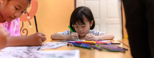 亚洲小女孩坐着练习他们的技巧 把注意力放在桌上的彩色纸上 学前儿童在家学习写作和阅读 艺术教育和创造力 儿童活动 — 图库照片