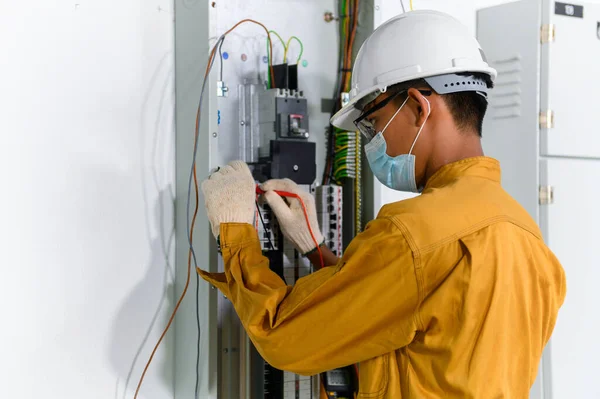 新しい建物の電力制御室で電気設備や配線作業をテストするための制御パネルのデジタルマルチメータテスト電流電気を使用して電気技師 — ストック写真