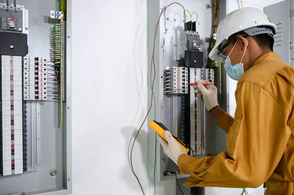 新しい建物の電力制御室で電気設備や配線作業をテストするための制御パネルのデジタルマルチメータテスト電流電気を使用して電気技師 — ストック写真