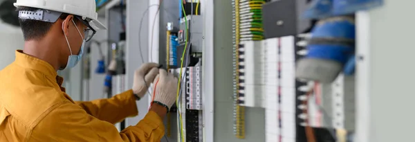电工工程师在控制面板中使用数字万用表测试电流来测试新大楼动力控制室的电气装置和接线工作 — 图库照片
