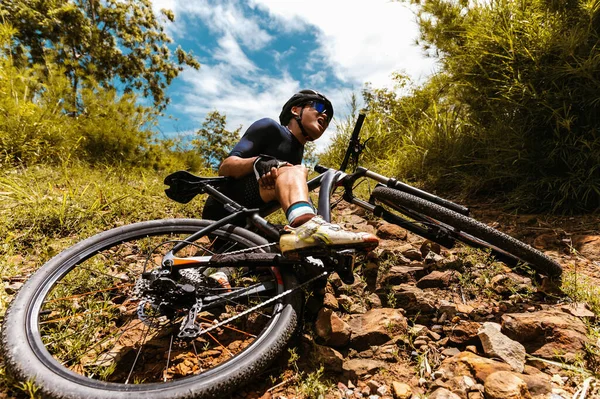 Cyclist accident falling off mountain bike and knee injury at MTB track. Athlete accident in crash and dangerous on trail in forest.