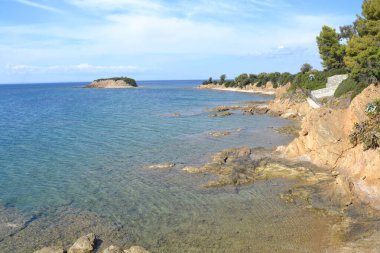 Turkuaz suları, kayalık kıyı şeridi ve parlak mavi gökyüzünün altındaki agave bitkileriyle çarpıcı bir kıyı manzarası. Akdeniz doğasının, huzurun ve yaz manzarasının mükemmel bir temsili..